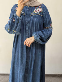 Blue denim dress with floral embroidery worn by a person against a plain background