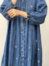 Denim dress with floral embroidery on a plain background