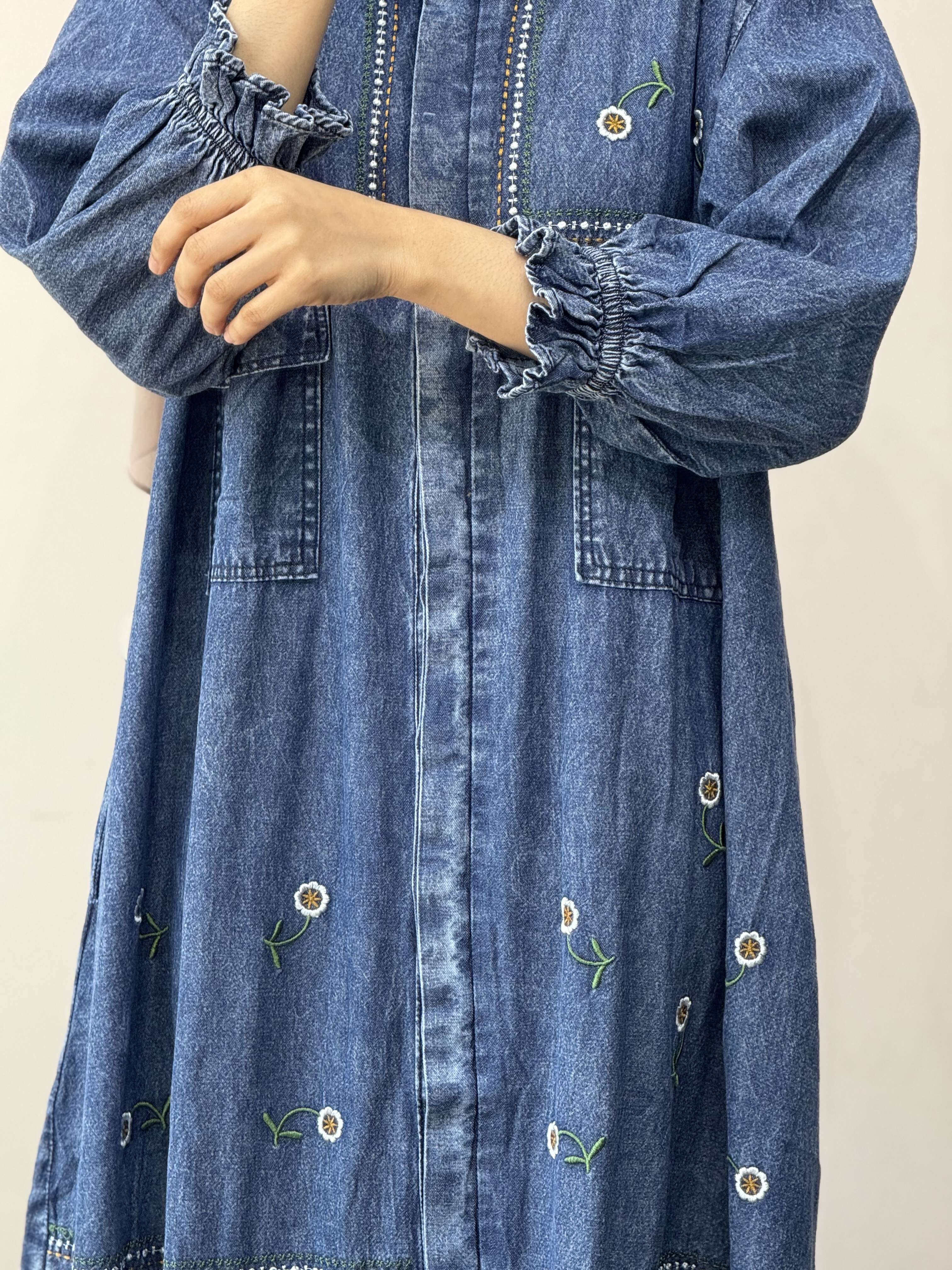 Denim dress with floral embroidery on a plain background