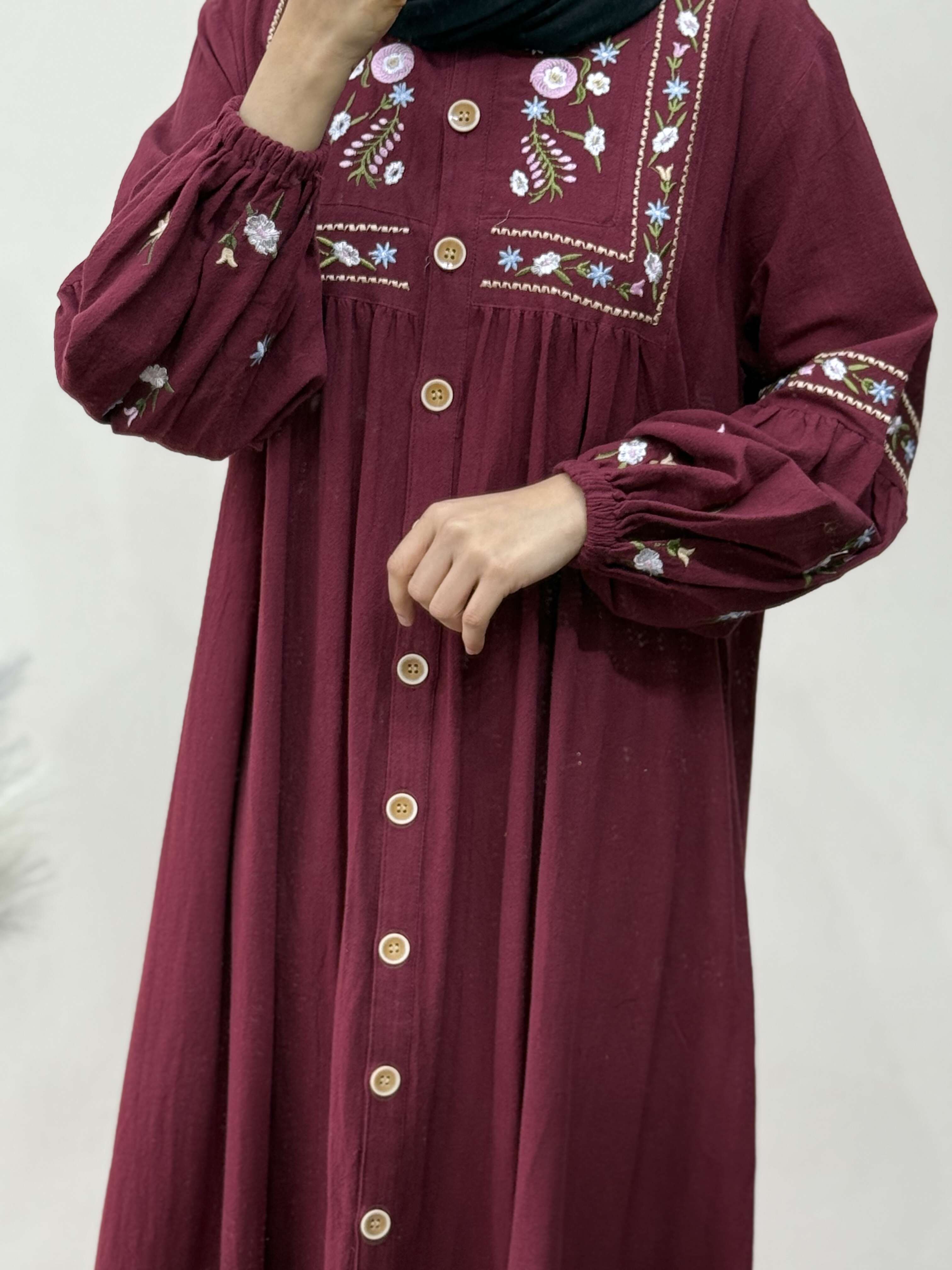 Maroon dress with floral embroidery on a plain background