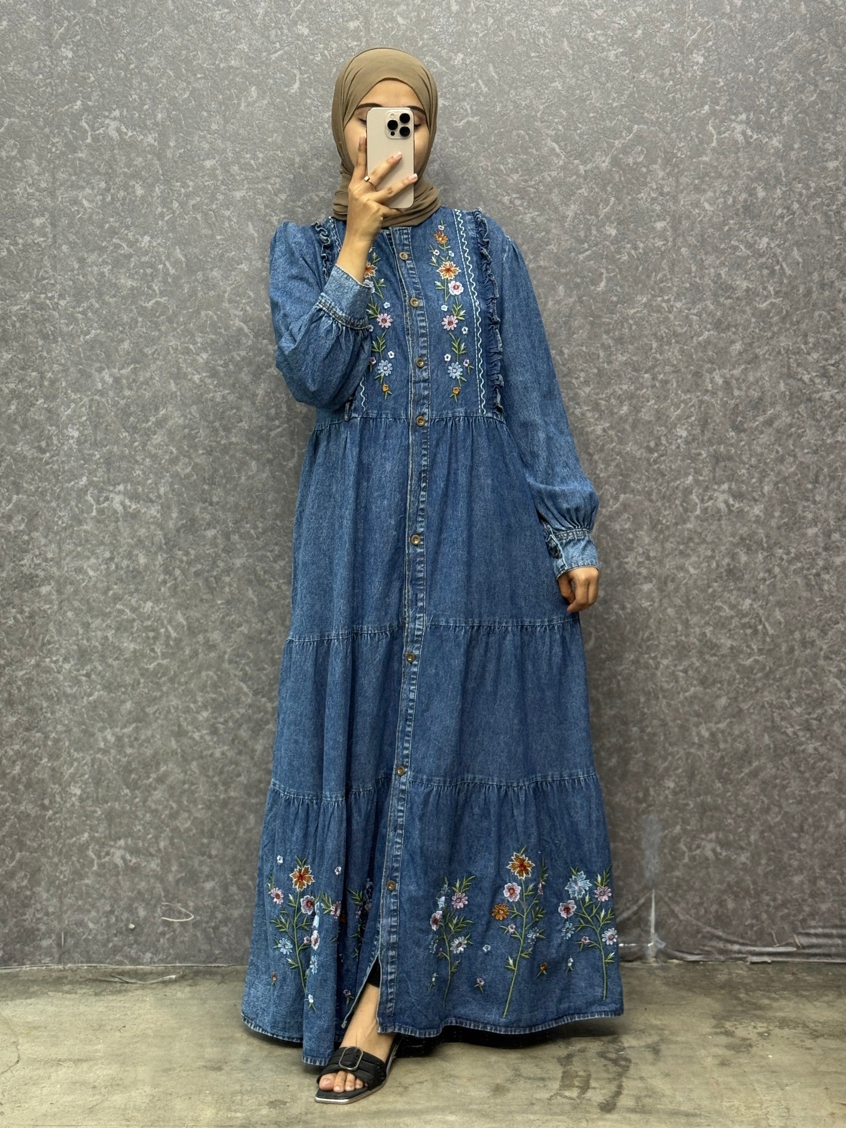 Woman wearing a blue embroidered dress against a gray background