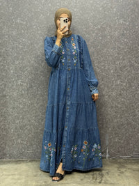 Woman wearing a blue embroidered dress against a gray background