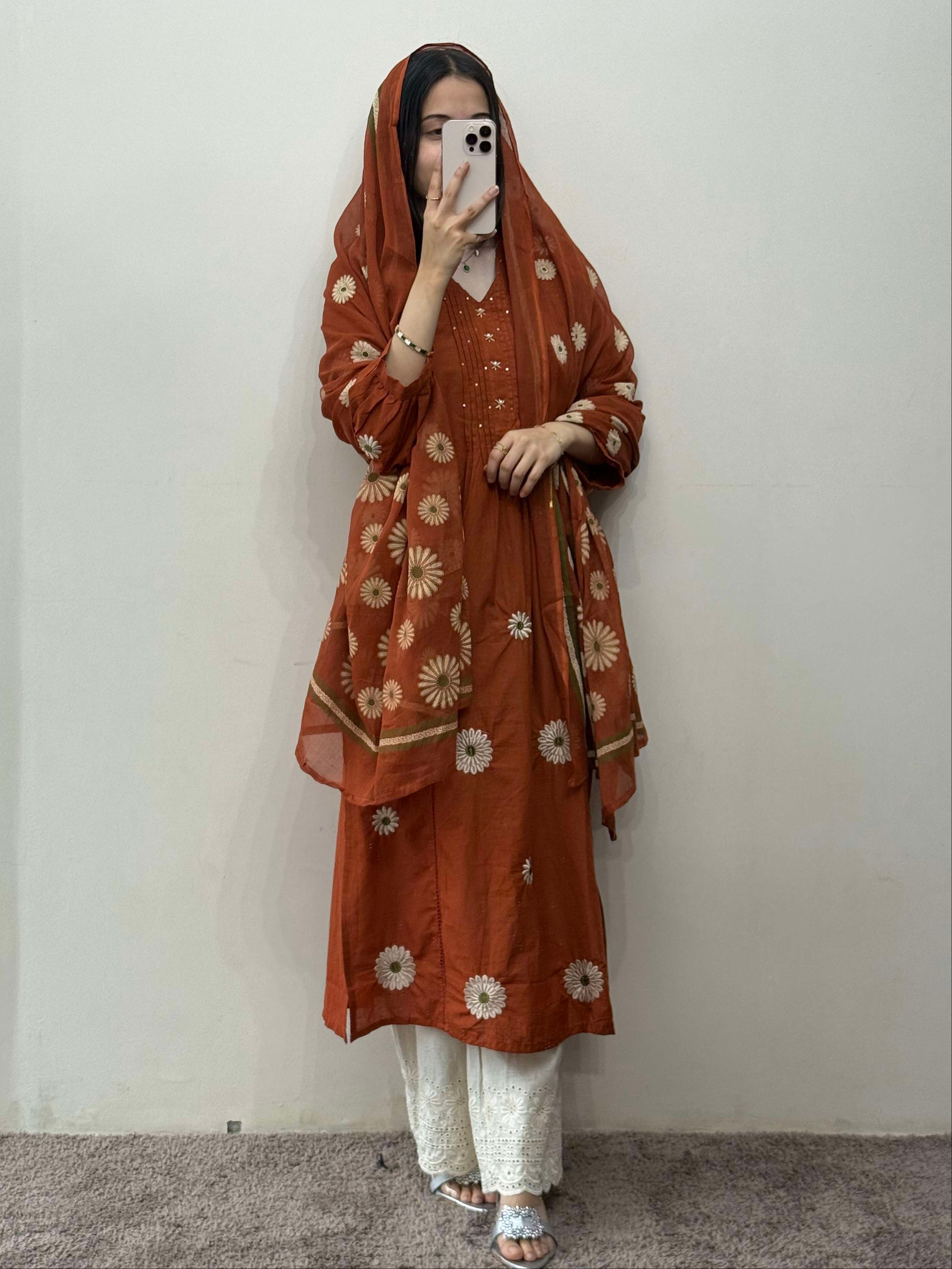 Person wearing a brown floral patterned outfit against a plain background