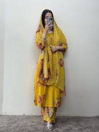 Person wearing a yellow traditional outfit with floral patterns against a plain background