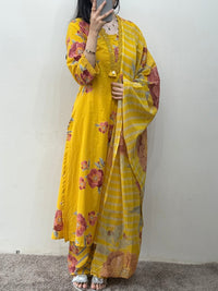 Person wearing a yellow floral outfit standing against a white wall.
