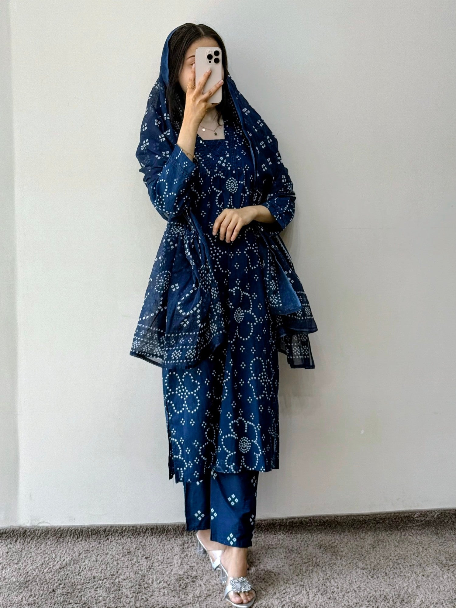 Person wearing a blue patterned outfit taking a mirror selfie against a plain background