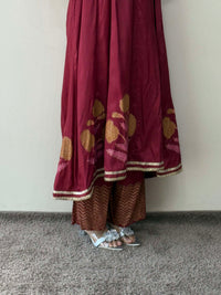 Maroon traditional outfit with gold embroidery on a plain background