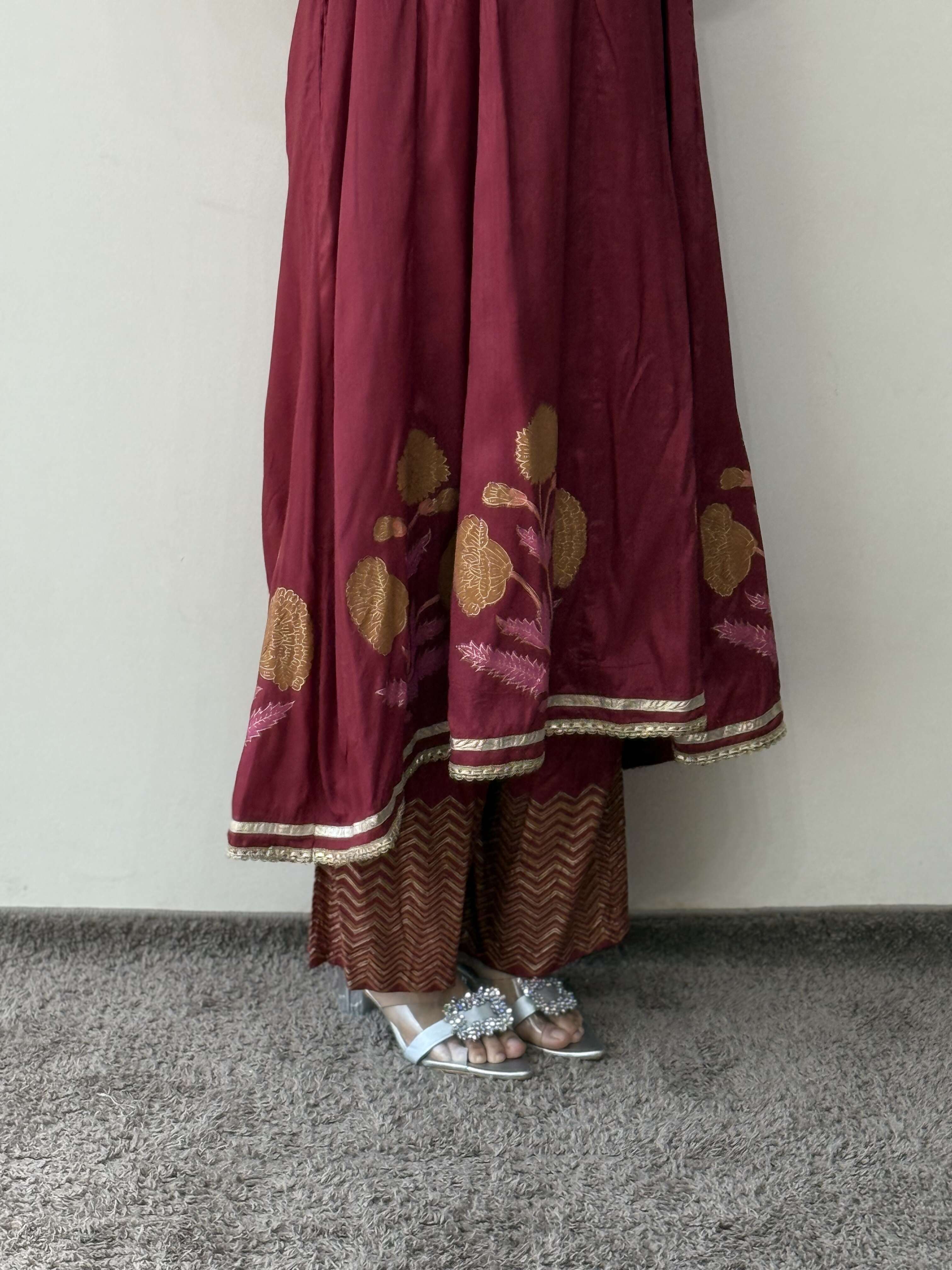 Maroon traditional outfit with gold embroidery on a plain background