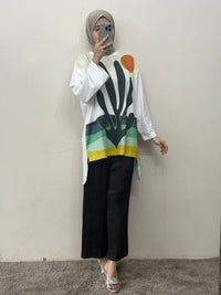 Person wearing a colorful top and black pants in front of a mirror.