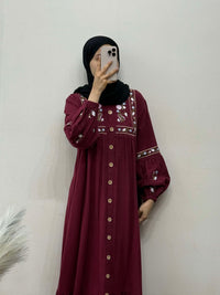 Person wearing a burgundy dress with intricate patterns against a plain background