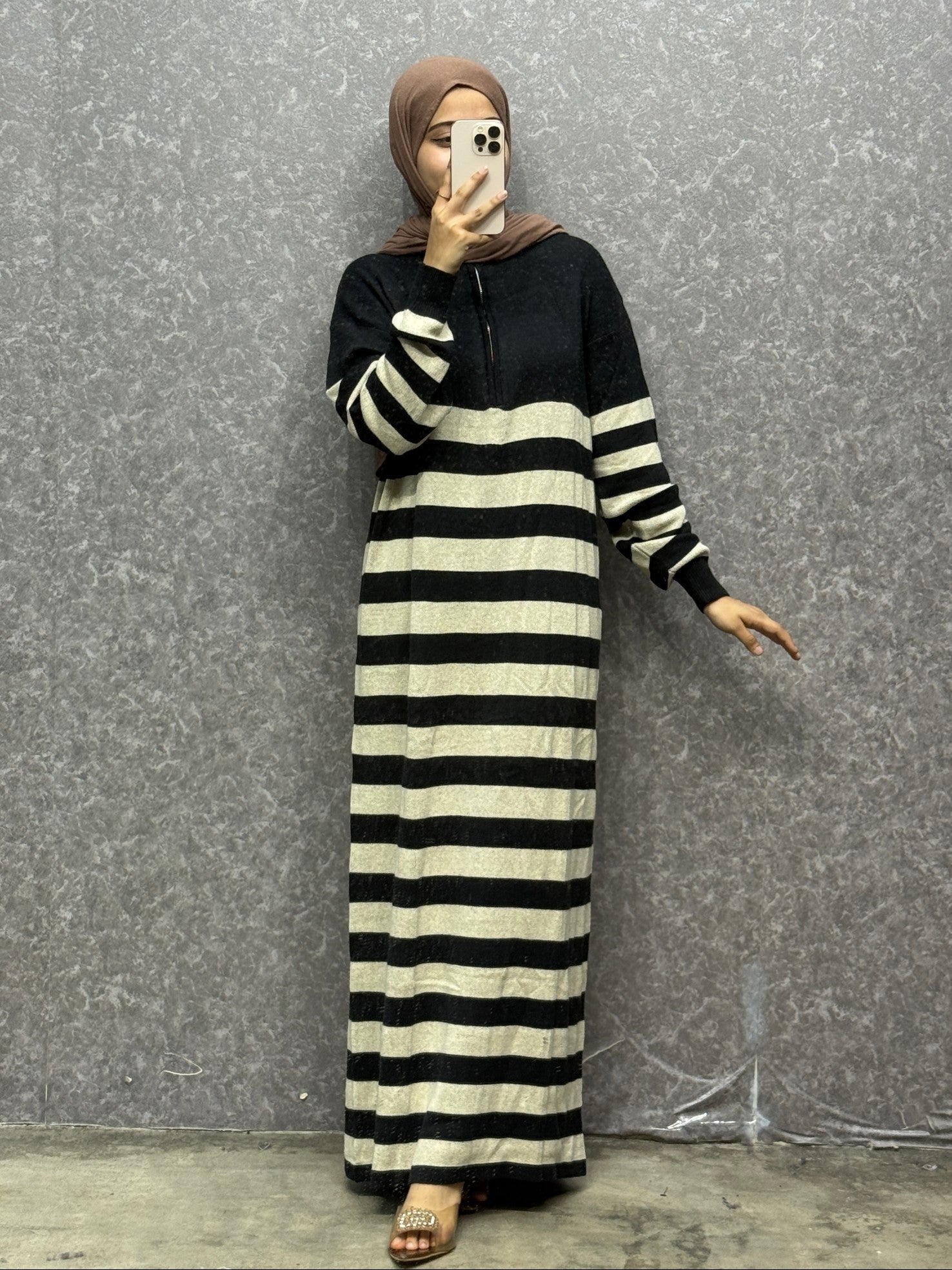 Person wearing a black and white striped dress against a gray background