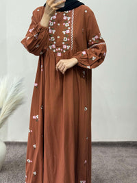 Brown dress with floral embroidery worn by a person against a plain background