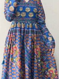 Person wearing a blue patterned dress against a plain background