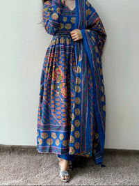 Person wearing a blue patterned dress against a white wall