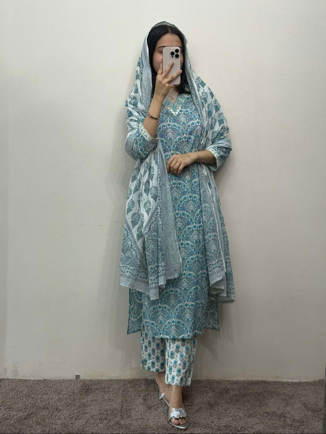 Woman wearing a blue and white patterned outfit against a plain background
