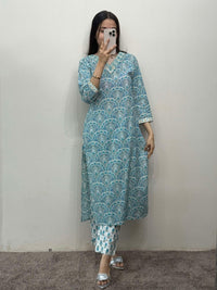 Person wearing a blue patterned kurta with white pants against a plain background